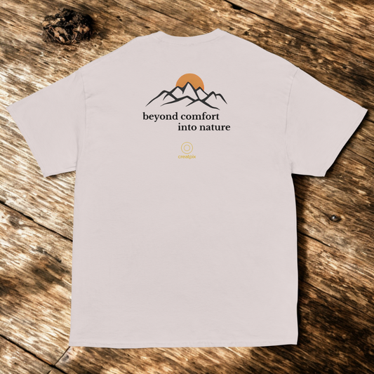 Back view of light grey tee with mountain outline and “beyond comfort into nature” text, wood flat-lay.
