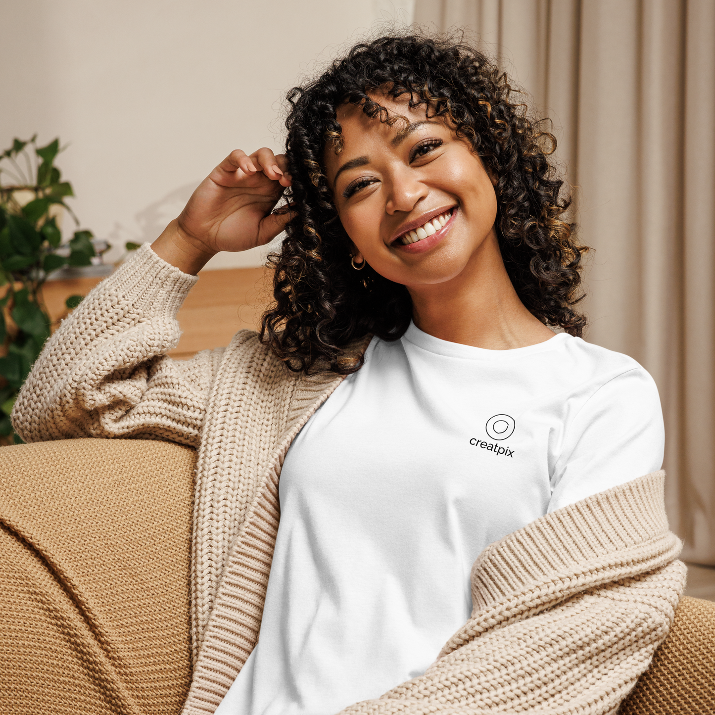 Lifestyle shot of model lounging on a sofa wearing the white portrait tee, cozy living-room setting.