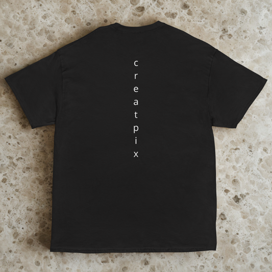 Back view of charcoal tee with slim vertical “creatpix” wordmark down the center, light speckled stone surface.