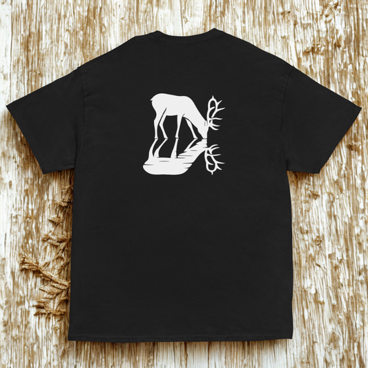Back view of charcoal tee with white stag drinking and mirrored antlers, rustic wood plank surface.