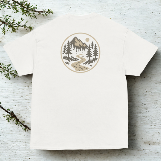 Back view of white tee with small round badge showing a river winding through evergreen forest, clean neutral backdrop.