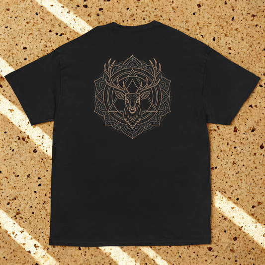 Back view of charcoal tee with angular stag head emblem, dappled window shadows on speckled stone.