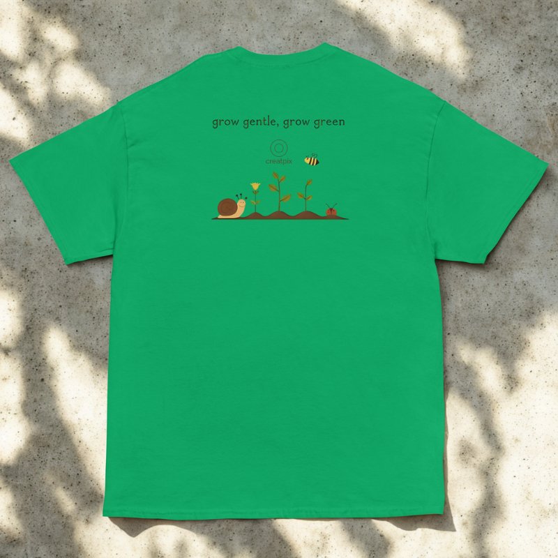 Back view of green tee with tiny garden illustration and line quote, sunlit flat-lay near foliage.