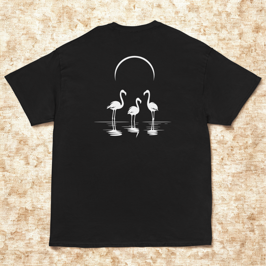 Back view of charcoal tee with three flamingos standing in water under a crescent, warm woven canvas background.