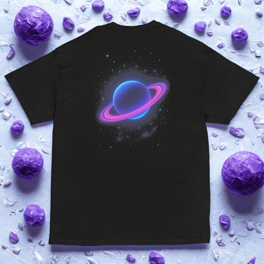 Back view of charcoal tee with glowing blue planet and magenta rings, purple stones scattered on light surface.
