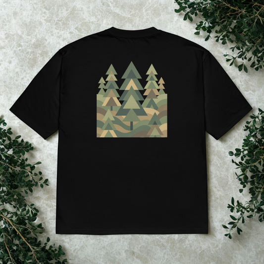 Back view of charcoal tee with large geometric forest triangles pattern, soft window shadows on neutral stone.