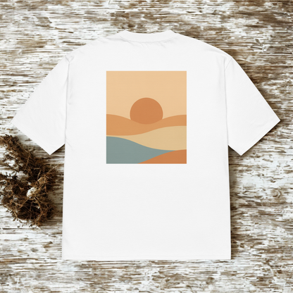 Back view of white tee with small square minimalist sunset landscape illustration, rustic wood backdrop.