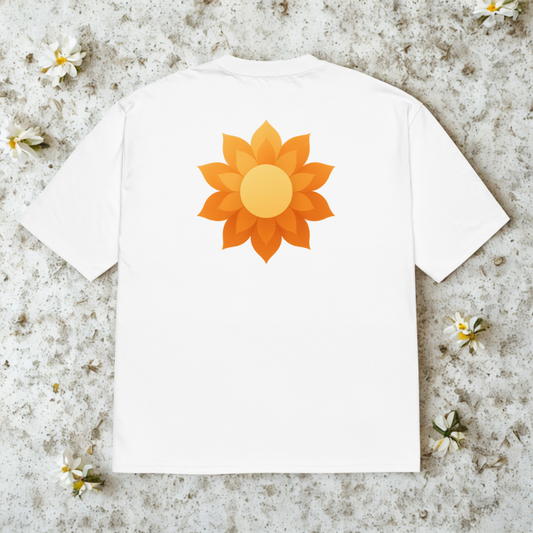 Back view of white tee with large orange sunrise-blossom graphic, soft shadows on pale concrete.