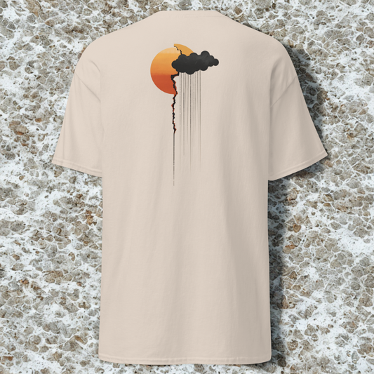 Back view of sand tee with small orange sun and dark rain cloud dripping lines near the left shoulder, speckled stone backdrop.