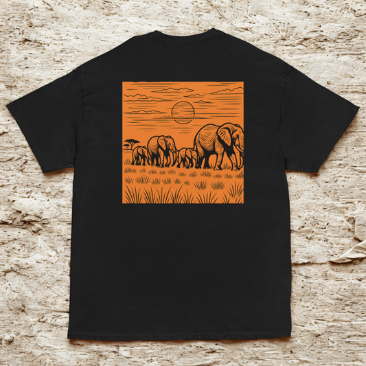 Back view of charcoal tee with orange square safari scene of marching elephants at sunset, textured stone backdrop.