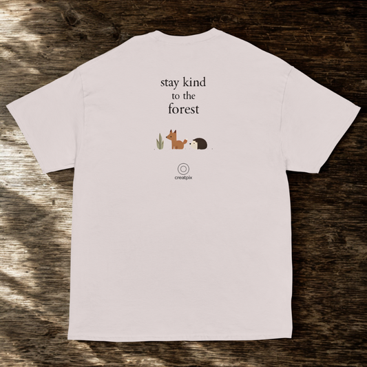 Back view of beige tee with small “stay kind to the forest” quote and cute forest icons, wood backdrop.