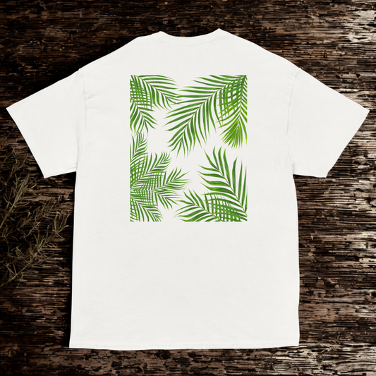 Back view of white tee with bright green palm fronds forming a square frame, dark wooden backdrop.