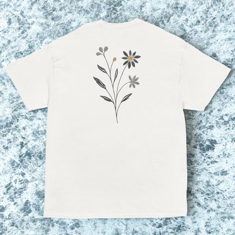 Back view of white tee with delicate single wildflower stem centered high, cool marble backdrop.